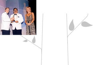 Man receiving an award on stage with presenters during a formal ceremony